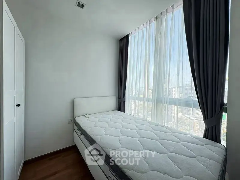 Bright bedroom with large window and city view, featuring a comfortable bed and modern design.