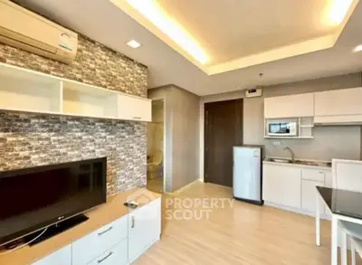 Modern open-layout living room with kitchen, featuring stylish brick accent wall and sleek appliances.