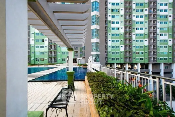 Modern apartment complex with pool and garden view, featuring stylish architecture and lush greenery.
