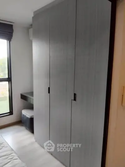 Modern bedroom with sleek wardrobe and natural light from large window.