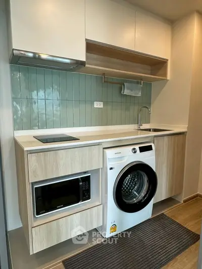 Modern kitchen with washing machine and microwave in compact layout