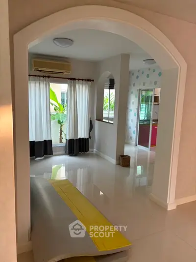Spacious living area with archway and large windows, perfect for natural light.