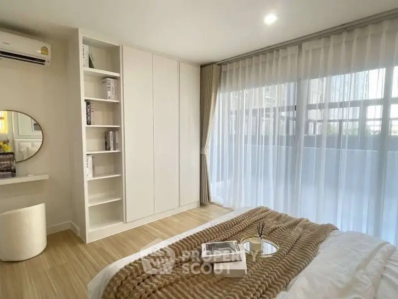 Modern bedroom with large window and stylish decor, featuring a cozy bed and built-in storage.