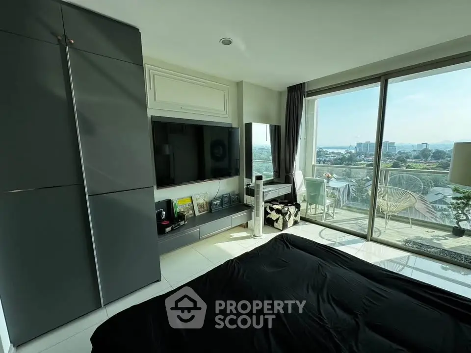 Modern bedroom with sleek design and stunning city view from large balcony.