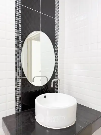 Modern bathroom with stylish black and white tiles and round mirror