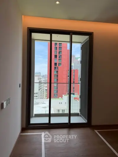 Modern apartment with floor-to-ceiling window offering cityscape views, featuring sleek wooden flooring.