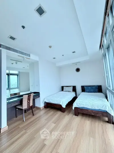 Spacious bedroom with twin beds and city view, featuring modern decor and ample natural light.