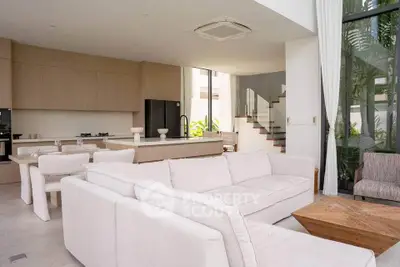 Luxurious open-plan living room with modern kitchen and elegant staircase in a contemporary home.