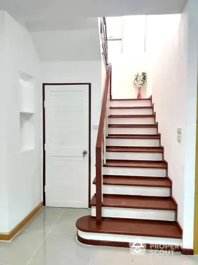 Modern staircase with sleek wooden steps and white walls in a bright home interior