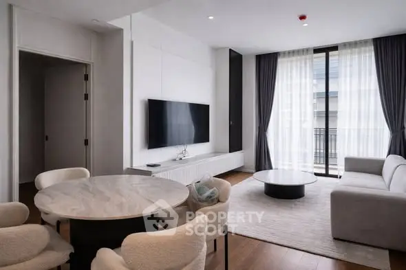 Modern living room with sleek furniture and large TV, featuring a cozy dining area and floor-to-ceiling windows.