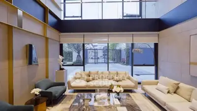 Luxurious modern living room with high ceilings and large windows offering garden views.