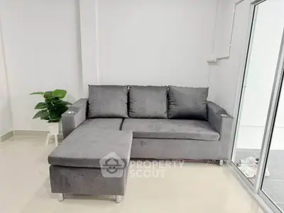 Modern living room with sleek gray sofa and glass sliding doors, perfect for contemporary urban living.