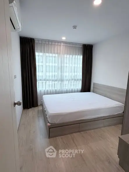 Modern bedroom with large window and minimalist design in urban apartment.