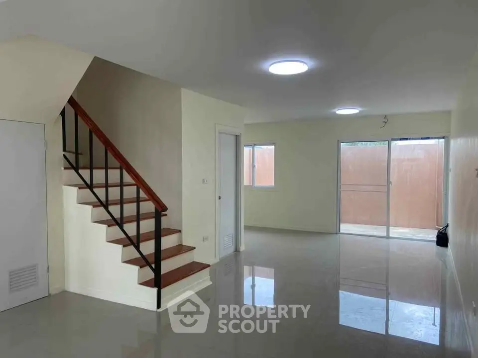 Spacious modern living room with sleek staircase and large windows for natural light.