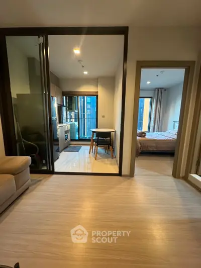 Modern apartment interior with open layout, featuring cozy living area, dining space, and bedroom view.