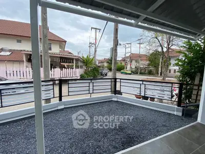 Charming residential neighborhood view from a spacious balcony with modern railing.