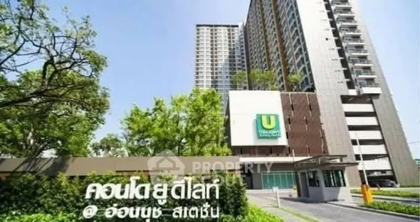 Modern condominium building with lush greenery and clear signage in urban setting.