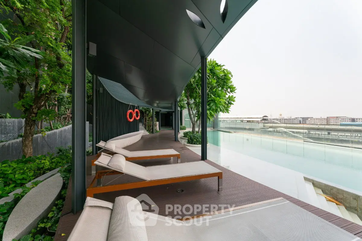 Luxurious poolside area with modern lounge chairs and lush greenery, offering a serene urban retreat.