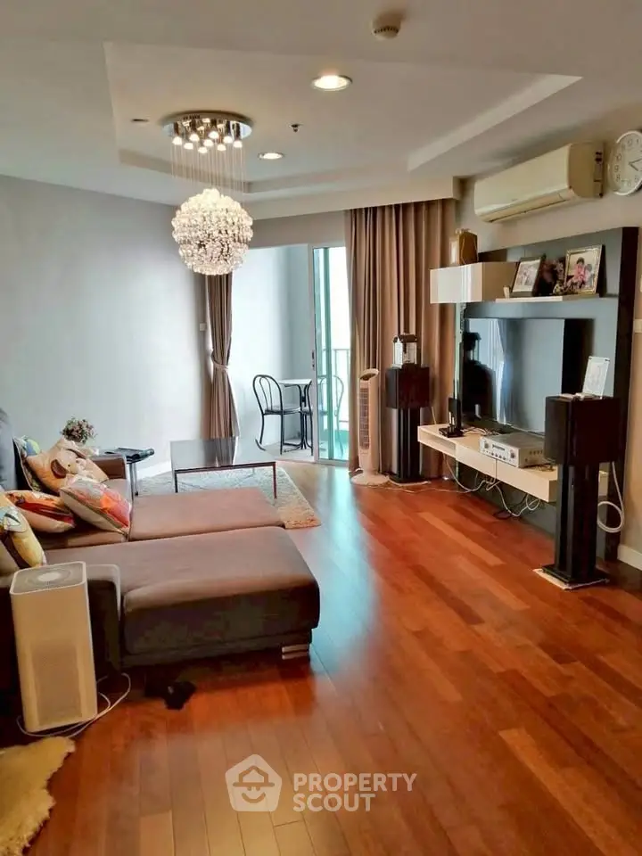 Spacious living room with modern decor and balcony access, featuring hardwood floors and stylish lighting.