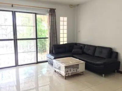 Spacious living room with modern black sectional sofa and large windows.