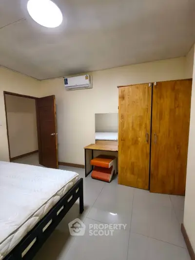 Cozy bedroom with wooden furniture and air conditioning in modern apartment.