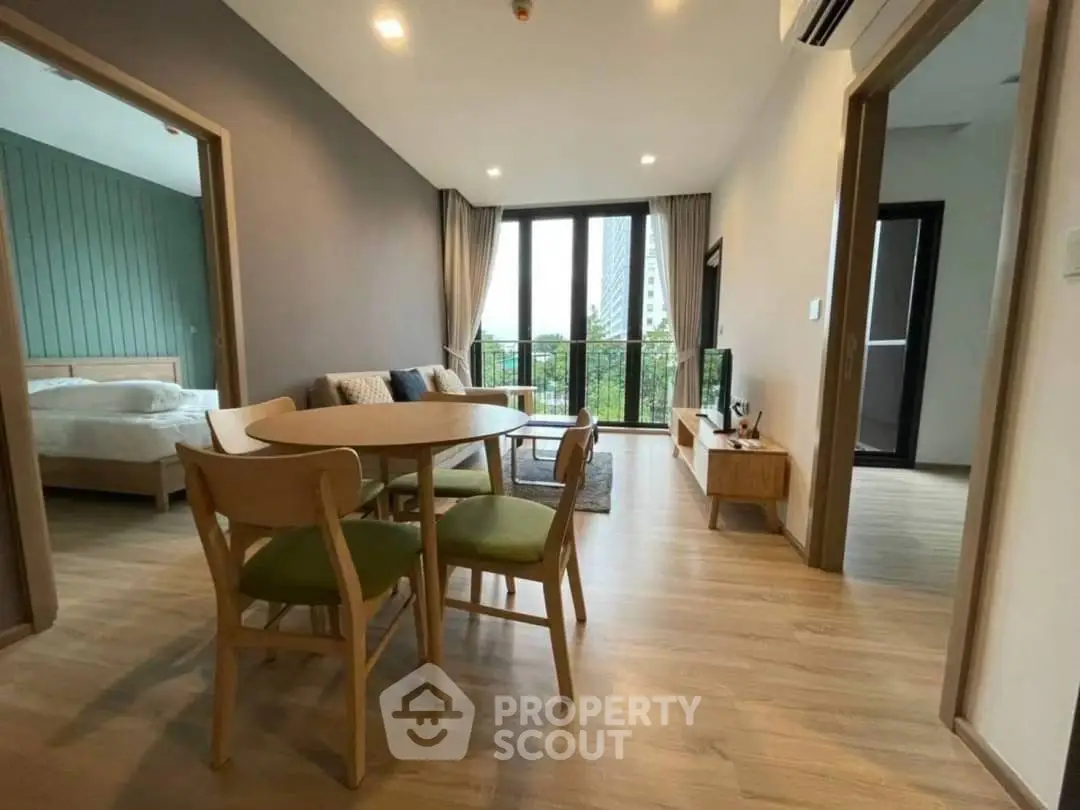 Modern apartment with open living room and dining area, featuring large windows and stylish decor.