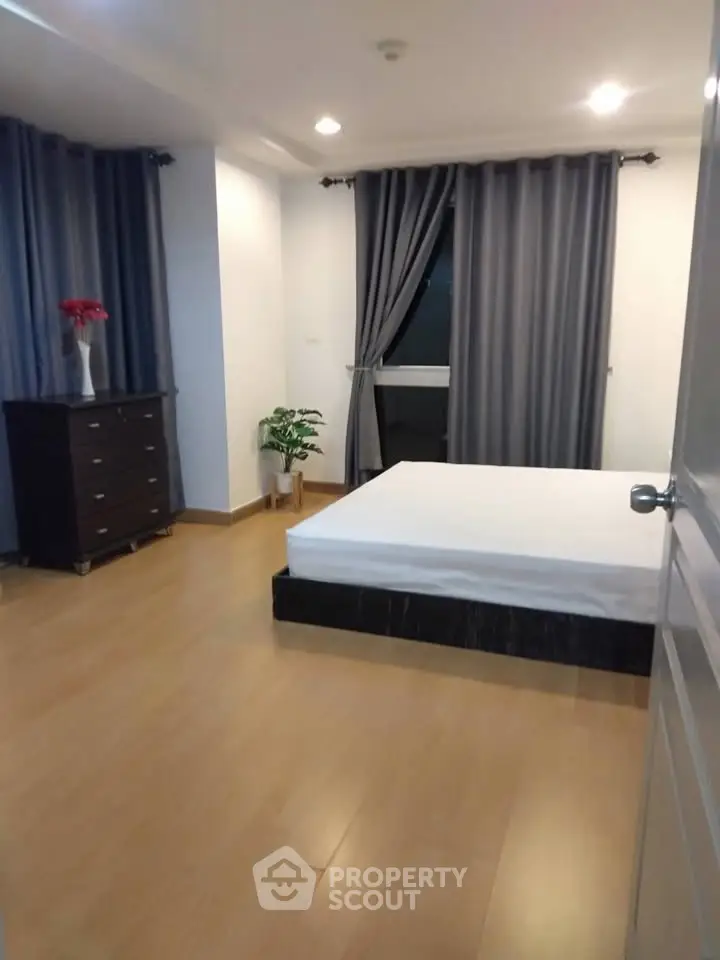 Spacious bedroom with modern decor and large window for natural light.