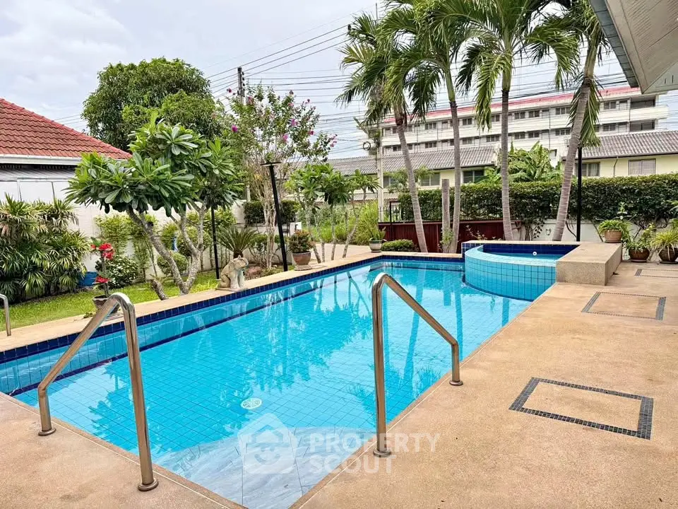 Charming residential pool area with lush greenery and palm trees, perfect for relaxation and leisure.