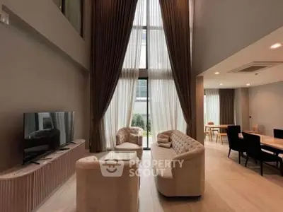 Luxurious high-ceiling living room with elegant furniture and large windows