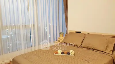 Cozy bedroom with large window offering stunning city views, featuring elegant decor and warm lighting.