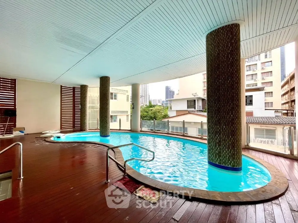 Luxurious indoor pool with city view in modern residential building.