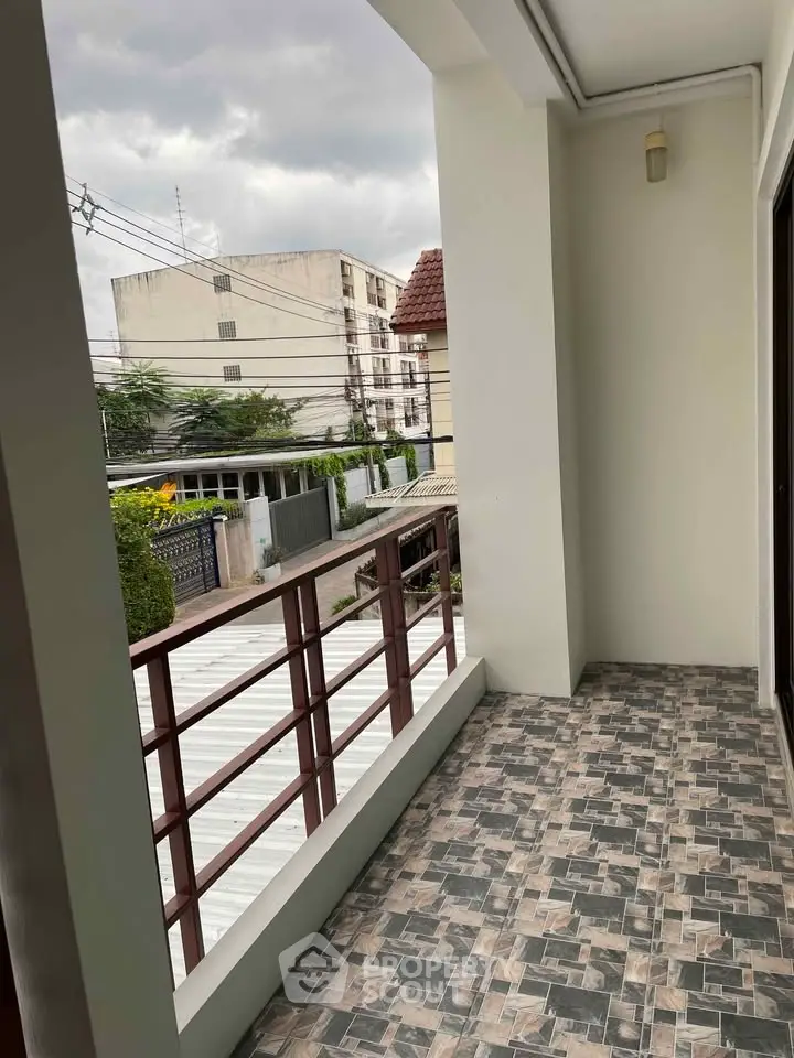 Spacious balcony with tiled flooring and urban view, perfect for relaxation.