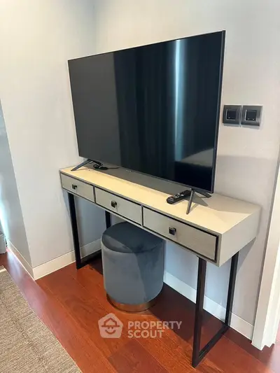 Modern living room with sleek TV setup on stylish console table, featuring hardwood floors and elegant decor.