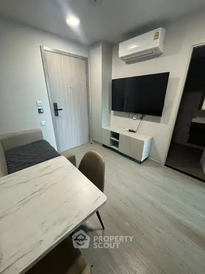 Modern living room with sleek furniture and wall-mounted TV in a cozy apartment.