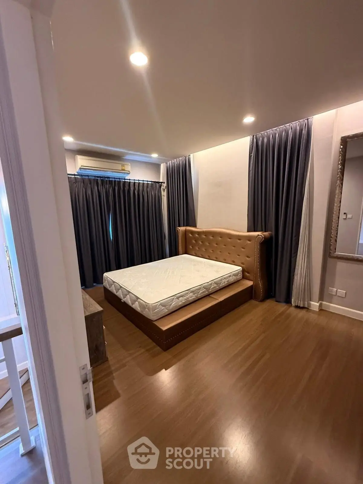 Spacious bedroom with elegant bed and floor-to-ceiling curtains, perfect for restful nights.