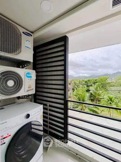 Modern balcony with washing machine and scenic view of lush greenery and mountains.