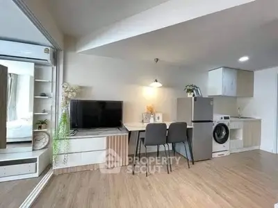 Modern open-plan living area with kitchen, dining, and laundry appliances in a stylish apartment.
