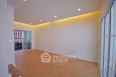 Spacious empty room with modern lighting and wooden flooring, perfect for customization.
