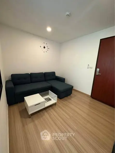 Modern living room with sleek wooden flooring and stylish dark sofa.