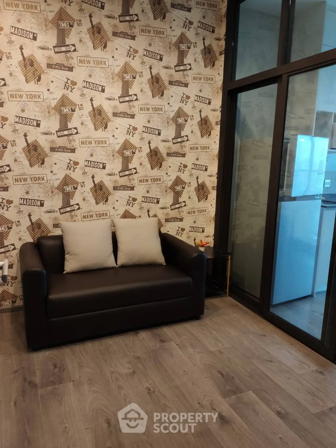 Stylish living room with modern decor and glass partition, featuring a cozy sofa and chic wallpaper.