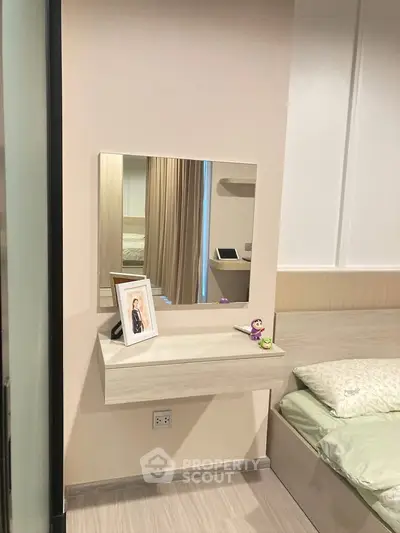 Modern bedroom with sleek vanity and mirror, featuring neutral tones and stylish decor.