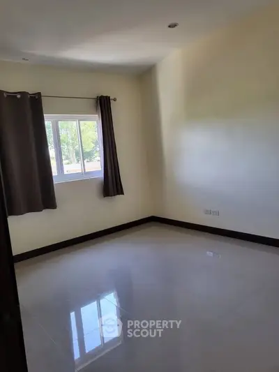 Spacious empty room with large window and glossy tiled floor, perfect for customization.