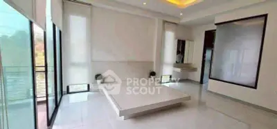 Spacious modern bedroom with minimalist design and large windows offering natural light.