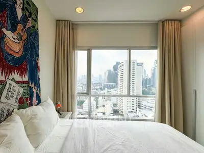 Modern bedroom with city view and artistic wall mural in high-rise apartment.