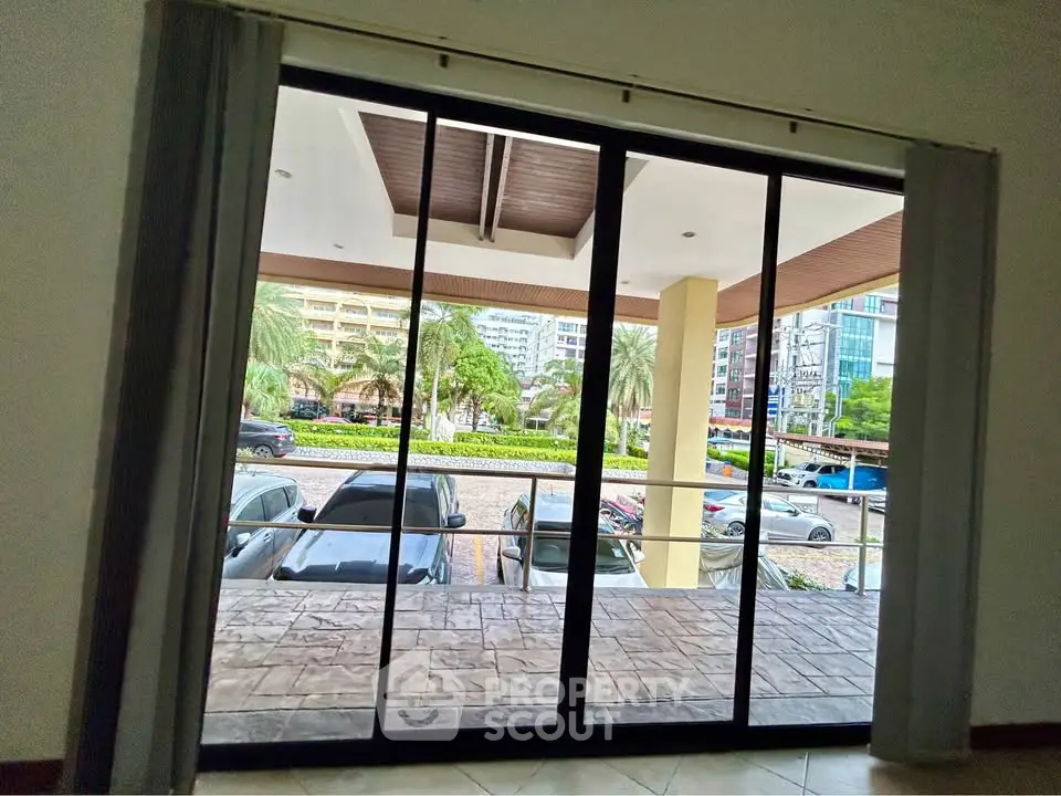 Spacious balcony view with sliding glass doors overlooking urban landscape and parked cars.