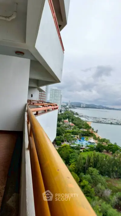 Stunning high-rise balcony view overlooking lush greenery and serene waterfront, perfect for relaxation.