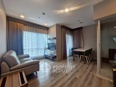 Modern living room with cozy seating and dining area, featuring large windows and stylish decor.