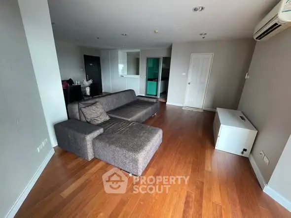 Spacious living room with modern sofa and hardwood flooring in a stylish apartment.