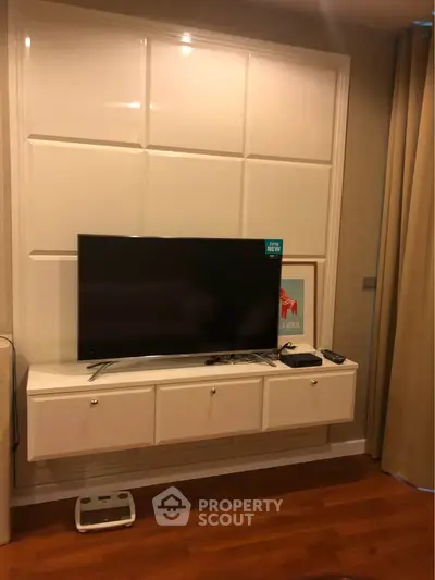 Modern living room with mounted TV and sleek storage unit on wooden floor.