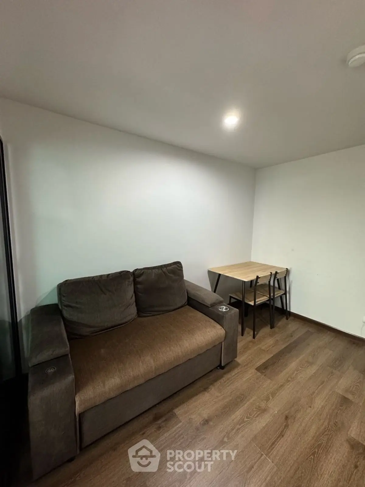 Cozy living room with modern sofa and compact dining table, perfect for urban living.